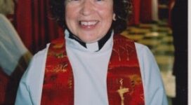 Photo of woman priest in red stole smiling. Rev. Bev Diet