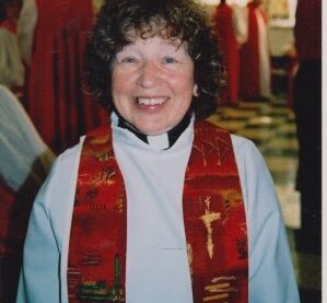 Photo of woman priest in red stole smiling. Rev. Bev Diet