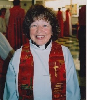 Photo of woman priest in red stole smiling. Rev. Bev Diet